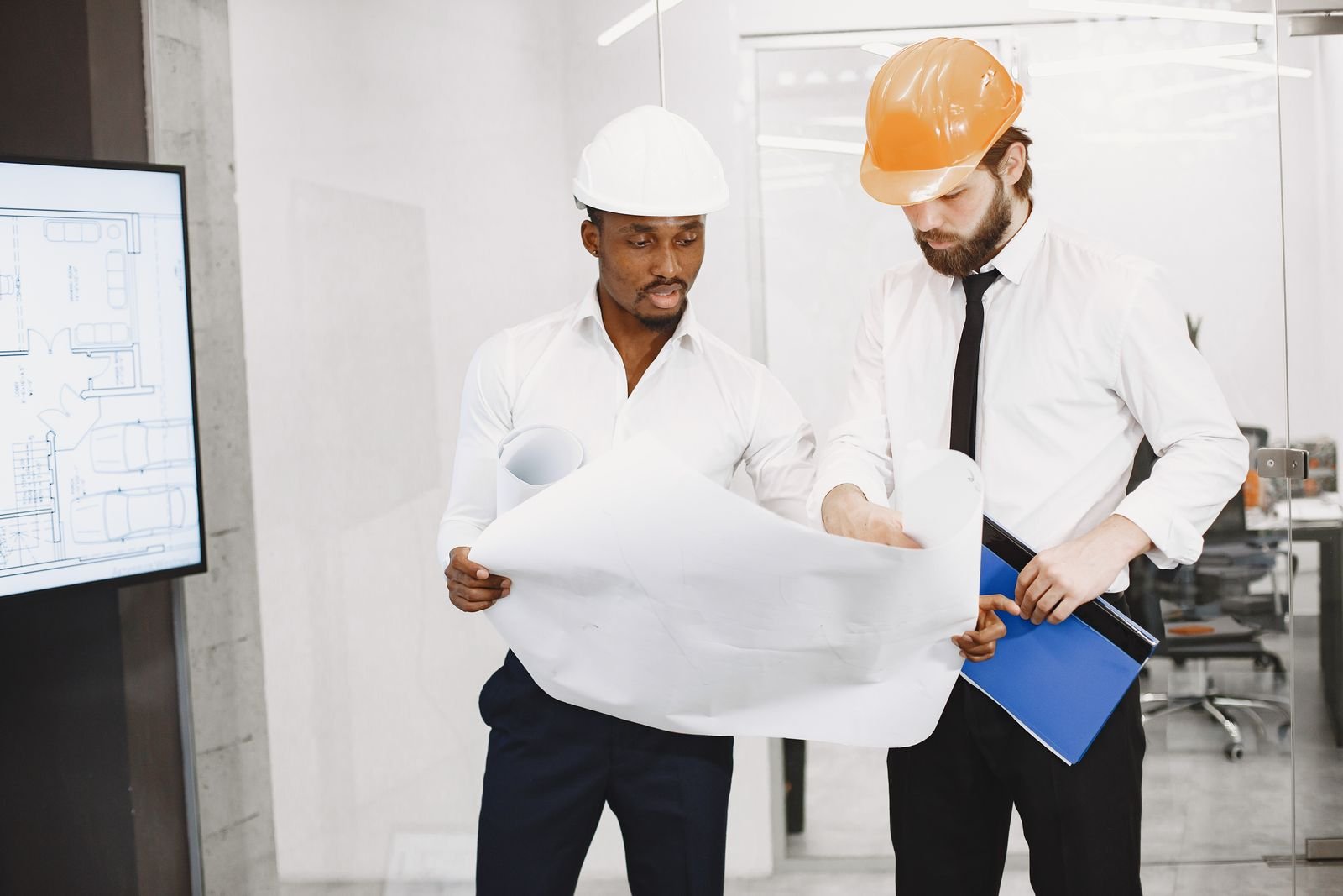 Twee mannen met bouwhelm bestuderen een bouwtekening