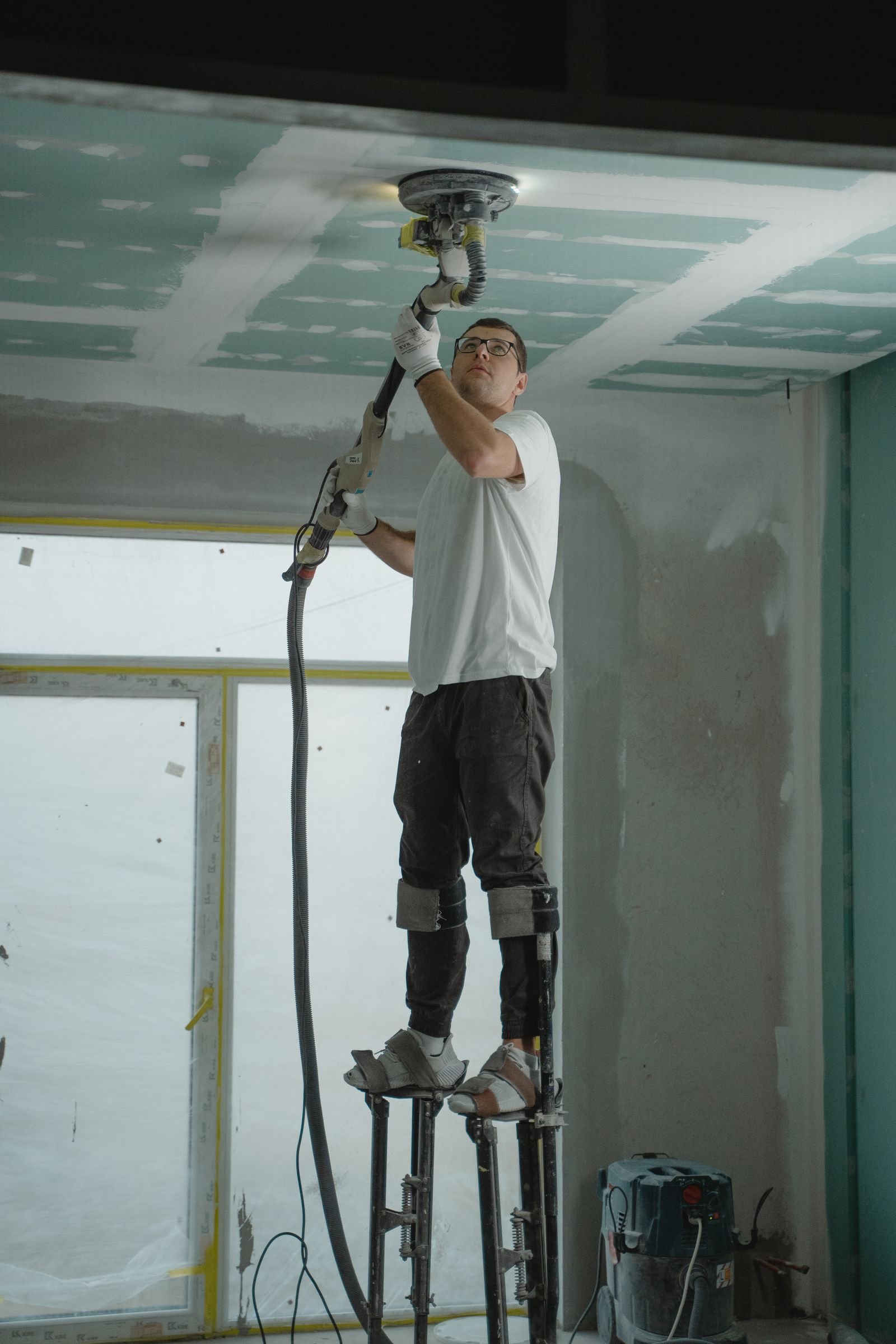 Vakman schuurt een plafond tijdens de afbouw